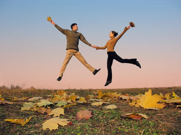 Pareja de salto. hojas de otoño. atardecer cielo — Foto de Stock