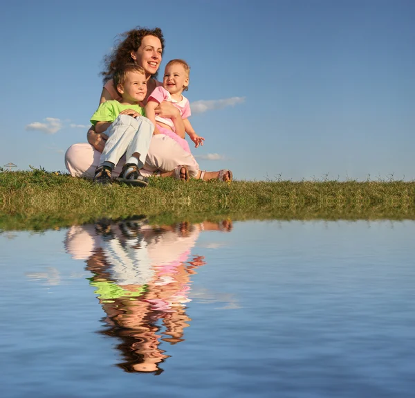 Мать с детьми на траве и воде — стоковое фото