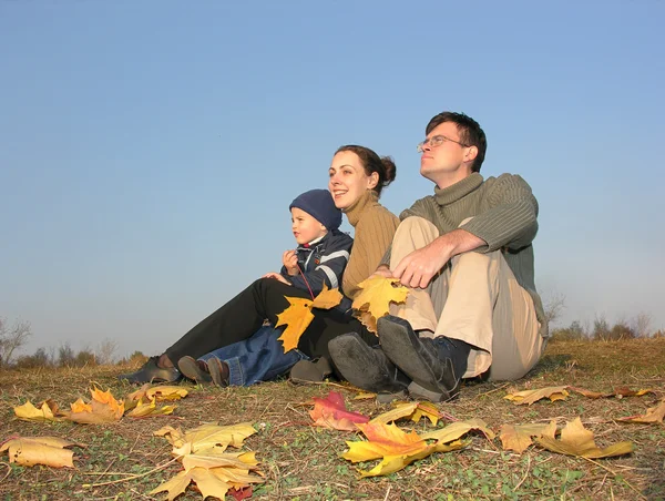 Familia sentarse con hojas de otoño — Foto de Stock