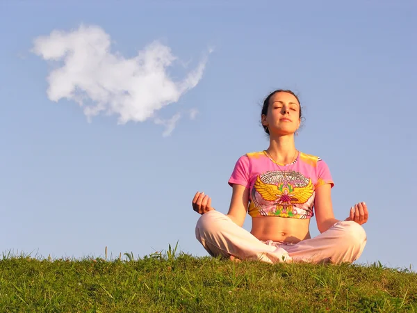 Девушка медитирует на лугу на фоне голубого неба — стоковое фото