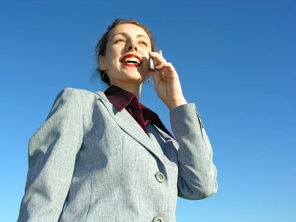 Geschäftsfrau mit Telefon am blauen Himmel von unten gesehen — Stockfoto
