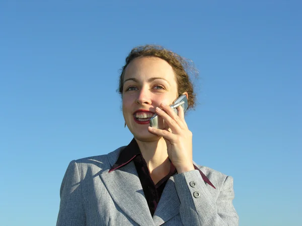 Businesswoman with phone on blue sky — Stock Photo, Image