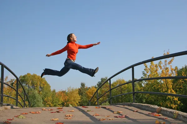 Meisje op herfst brug springen — Stockfoto