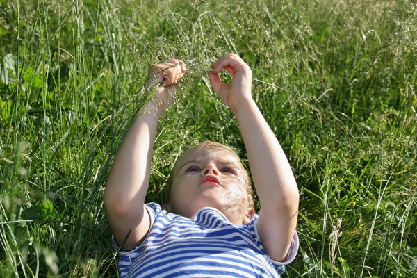Cabeça de criança encontra-se na grama — Fotografia de Stock