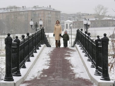 Mother with son on winter bridge clipart