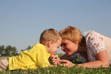 Mother with boy lies on meadow clipart