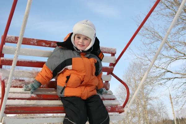Мальчик на зимних качелях — стоковое фото