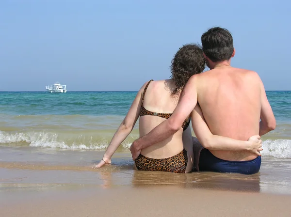 Detrás de pareja sentarse en la playa — Foto de Stock