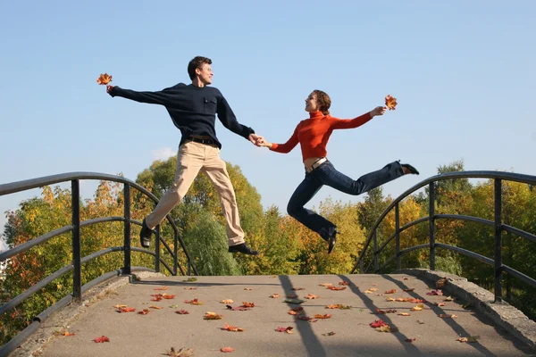 Salto pareja en otoño puente — Foto de Stock