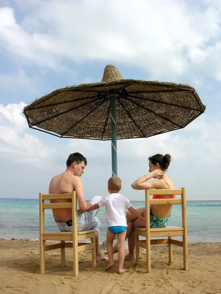 Aile plaj şemsiyesi altında — Stok fotoğraf
