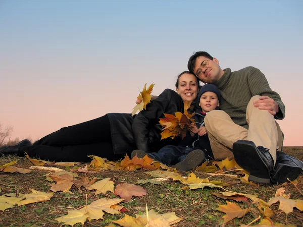 Familie met herfstbladeren en zonsondergang — Stockfoto