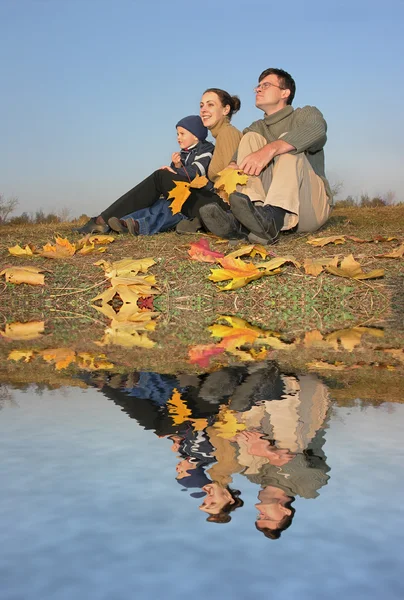 Familia sentarse con hojas de otoño — Foto de Stock