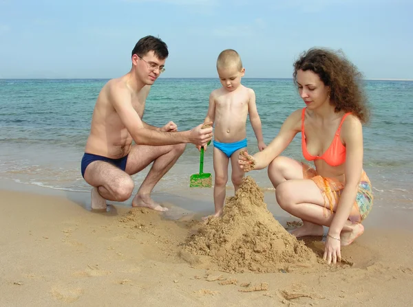 Семья строит песчаный замок на пляже — стоковое фото