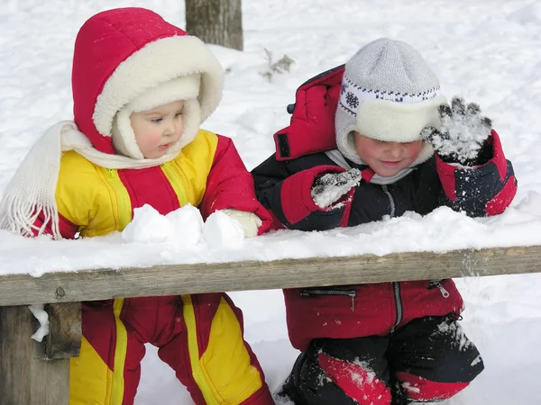Dítě a dítě hrát na lavičce. zimní. — Stock fotografie