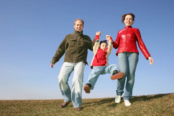Running family with child on spring meadow — Stock Photo, Image