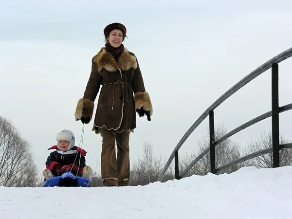 Мать с сыном на санях. зимний мост — стоковое фото