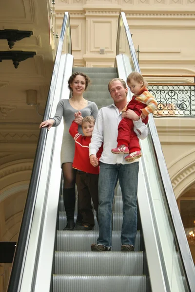 Familia de cuatro en escaleras mecánicas —  Fotos de Stock