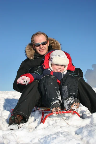 Зимний отец с ребенком на санях — стоковое фото