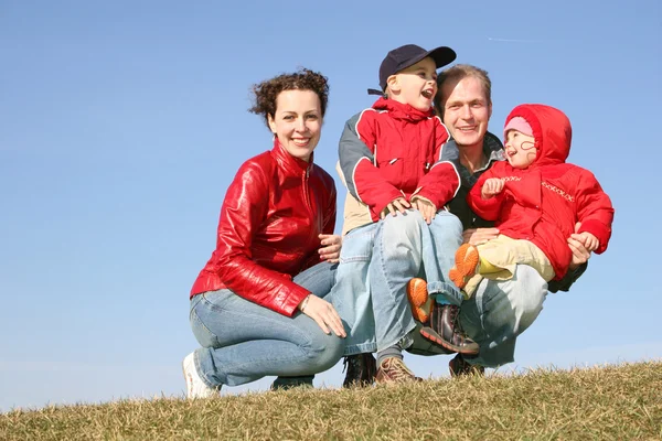Família de quatro sentar-se no prado da primavera — Fotografia de Stock