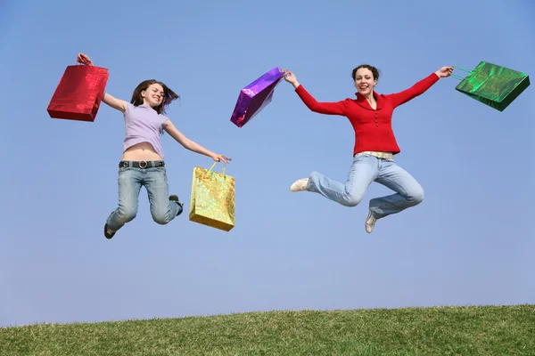 Jumping couple girls with bags — Stock Photo, Image