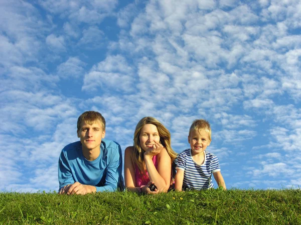Familie op kruid onder de blauwe hemel — Stockfoto