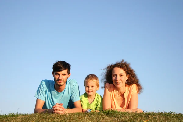 Familia sobre hierba bajo cielo azul mentira —  Fotos de Stock
