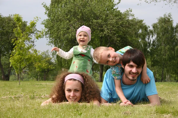 Семья из четырех человек лежит на траве 2 — стоковое фото