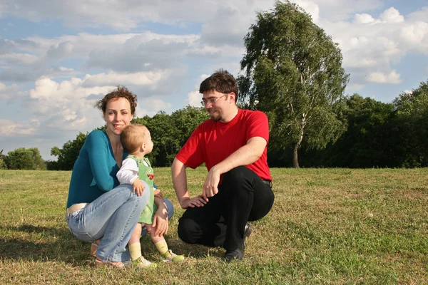 Familia woth bebé en prado y árboles — Foto de Stock