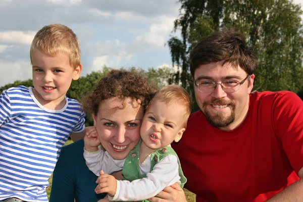 Familia con dos niños primer plano en el prado y los árboles —  Fotos de Stock
