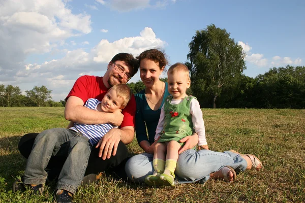 Famille avec deux enfants assis sur la prairie et les arbres 2 — Photo