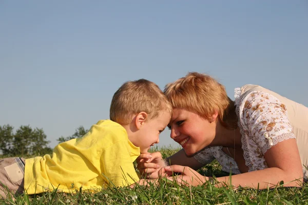 Mãe com menino encontra-se no prado — Fotografia de Stock