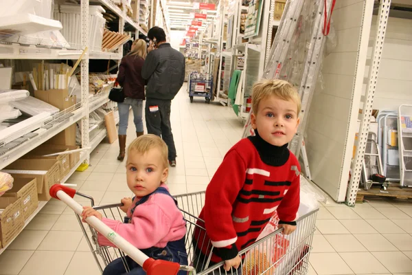 Children in shopingcart and couple — Stock Photo, Image