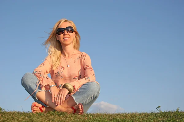 Sunglasse 的女人坐在草地上 — 图库照片