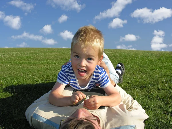 Son lie on ather on green grass — Stock Photo, Image
