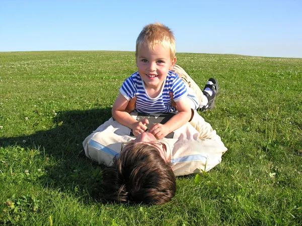 Сын лежит на отце на зеленой траве 2 — стоковое фото