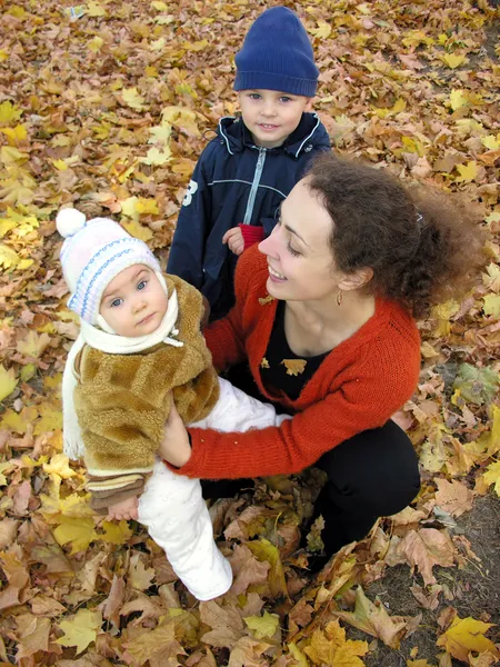 秋の葉の上の子供を持つ母 — ストック写真