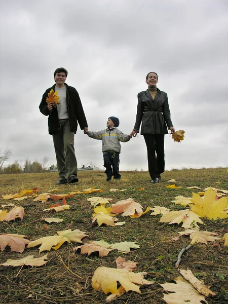 Famiglia che cammina con foglie e nuvole autunnali — Foto Stock