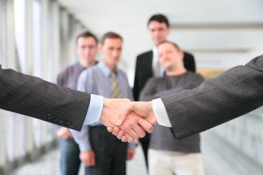 Shaking hands with wrists and business team 2 clipart