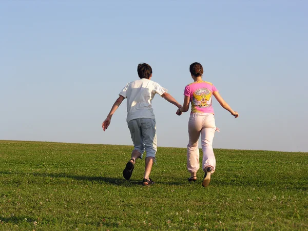 Correndo casal de volta grama céu — Fotografia de Stock