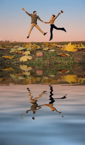 Άλμα ζευγάρι. Φθινοπωρινά φύλλα. ηλιοβασίλεμα νερό — Φωτογραφία Αρχείου
