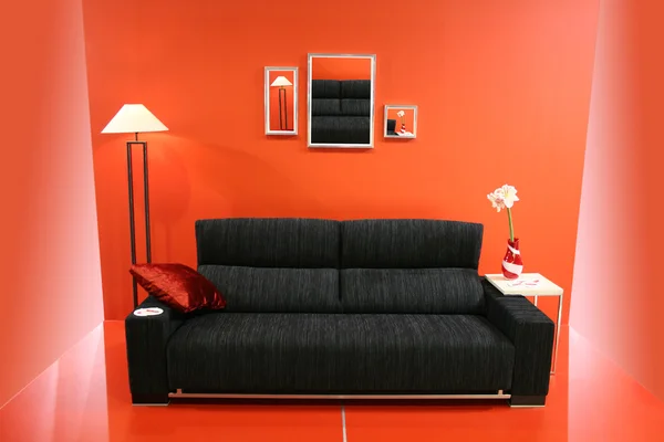 Sofá preto na parede vermelha — Fotografia de Stock