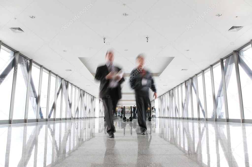 Moving businessmen and escalator