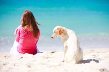 Aile ile tropik kumsalda beyaz köpek