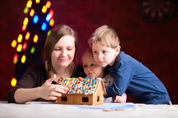 Mutter mit Kindern bastelt Lebkuchenhaus — Stockfoto