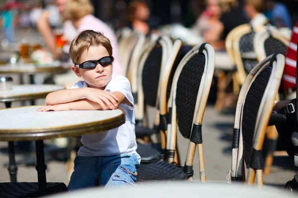 Симпатичный мальчик сидит в кафе на открытом воздухе — стоковое фото