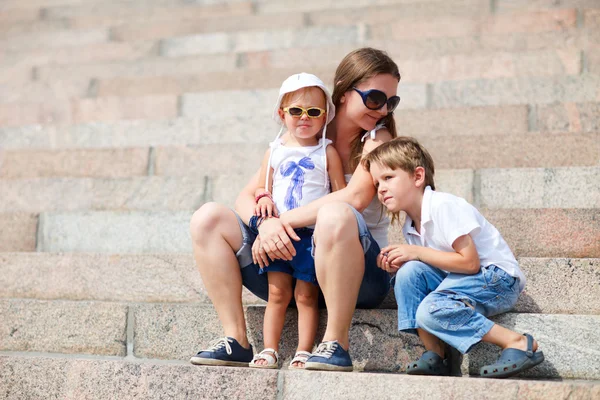 Matka a dvě děti sedí na schodech — Stock fotografie