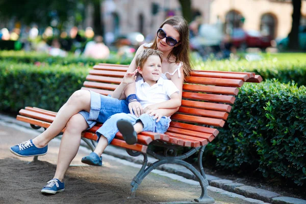 Matka a syn sedí na lavičce v parku — Stock fotografie