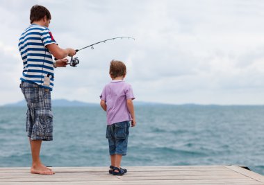 Baba ve oğul birlikte balık tutuyorlar.
