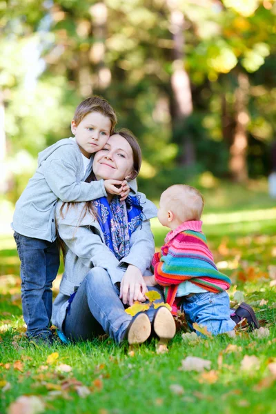 Μητέρα και δύο παιδιά που κάθεται στο γρασίδι — Φωτογραφία Αρχείου