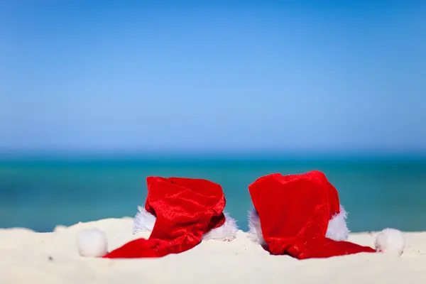 Sahilde iki kırmızı santa şapka — Stok fotoğraf